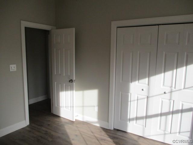 unfurnished bedroom featuring a closet, baseboards, and wood finished floors