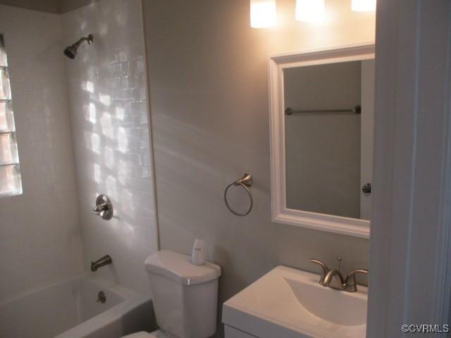 bathroom with washtub / shower combination, vanity, and toilet