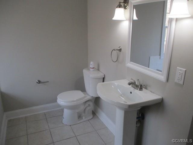 bathroom featuring toilet, tile patterned flooring, baseboards, and a sink