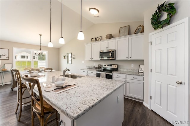 kitchen with a center island with sink, white cabinets, light stone counters, stainless steel appliances, and a sink