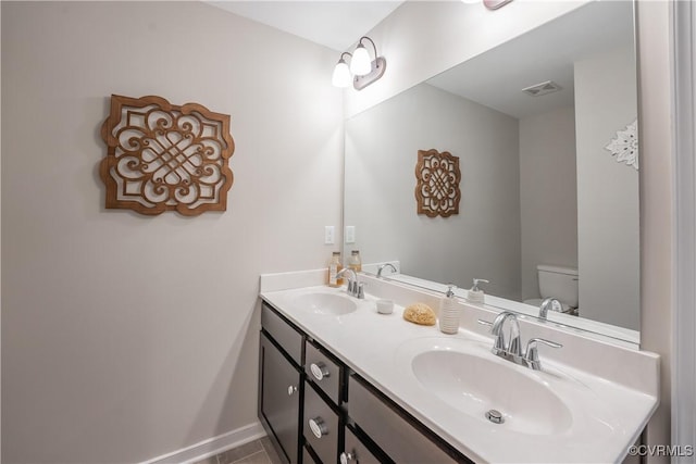 bathroom with toilet, double vanity, visible vents, and a sink