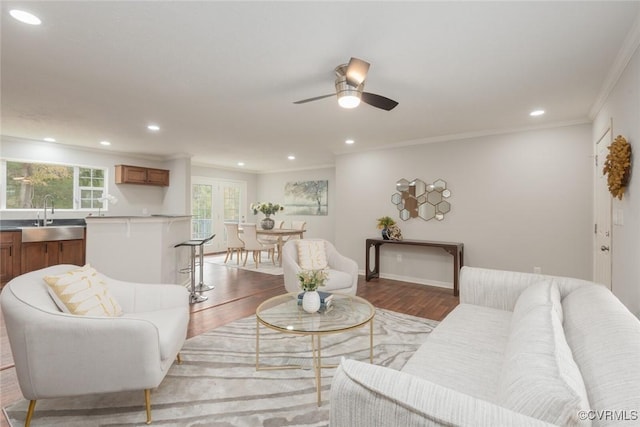 living area with recessed lighting, wood finished floors, a ceiling fan, baseboards, and crown molding