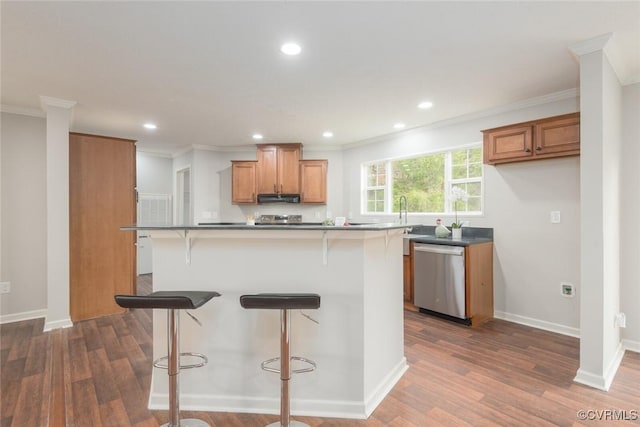 kitchen featuring dark countertops, dark wood-style floors, appliances with stainless steel finishes, and brown cabinets