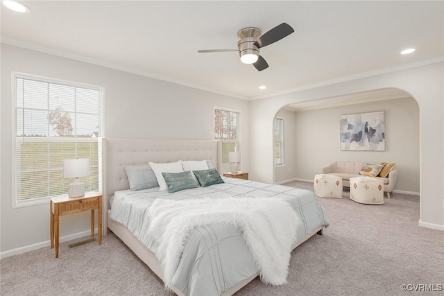 carpeted bedroom with arched walkways, multiple windows, crown molding, and baseboards