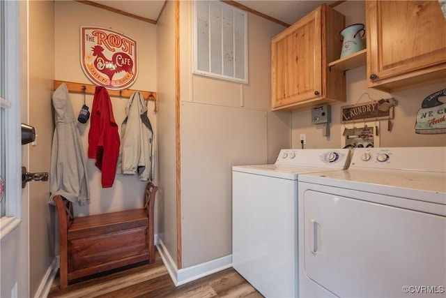 laundry room with wood finished floors, washing machine and dryer, cabinet space, crown molding, and baseboards