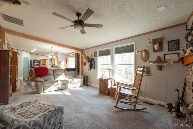 carpeted living room featuring visible vents, ceiling fan with notable chandelier, a textured ceiling, crown molding, and baseboards