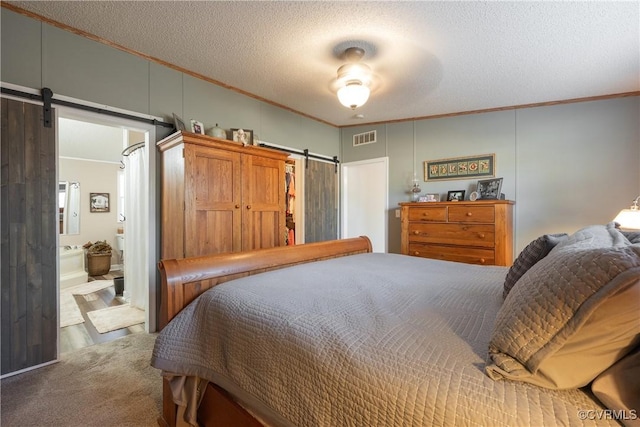 bedroom with visible vents, ornamental molding, ensuite bathroom, a textured ceiling, and a barn door