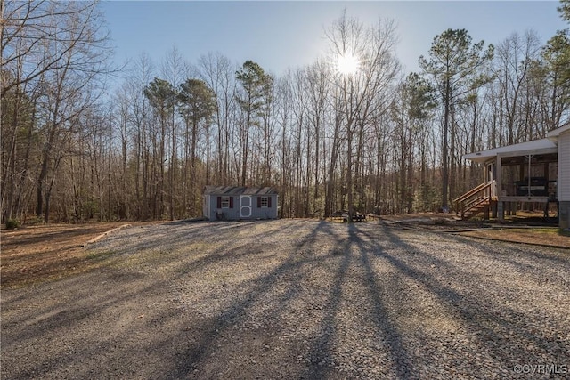 view of yard with an outdoor structure, driveway, and a shed