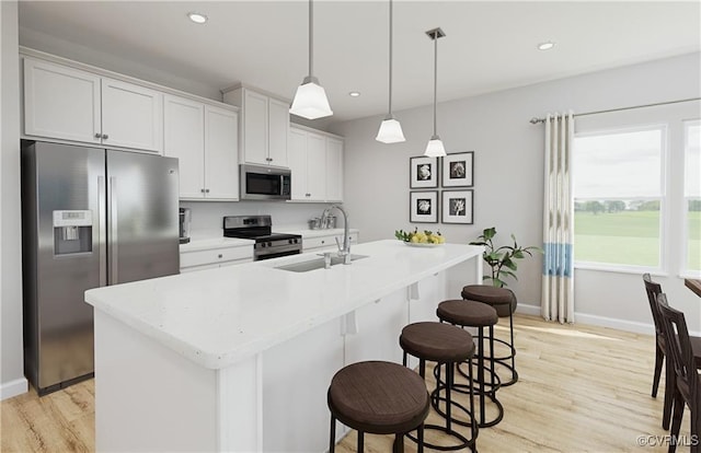 kitchen featuring stainless steel appliances, light countertops, a sink, and light wood-style flooring