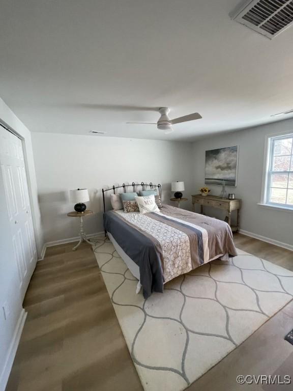 bedroom featuring ceiling fan, wood finished floors, visible vents, and baseboards