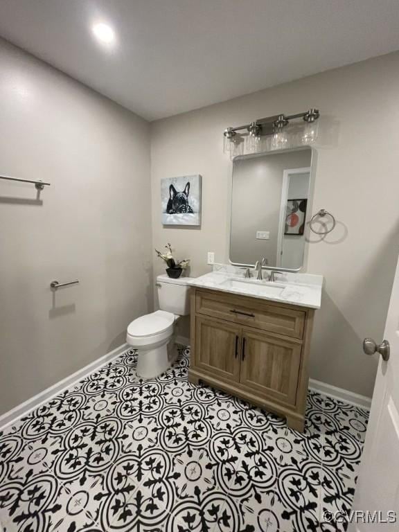 bathroom with tile patterned flooring, baseboards, vanity, and toilet