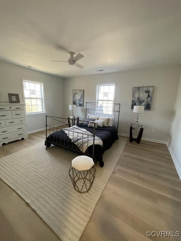 bedroom featuring multiple windows, wood finished floors, a ceiling fan, and baseboards