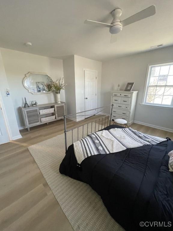 bedroom featuring ceiling fan, wood finished floors, visible vents, and baseboards