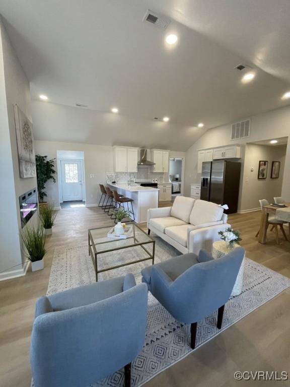 living area featuring light wood-style floors, lofted ceiling, visible vents, and recessed lighting