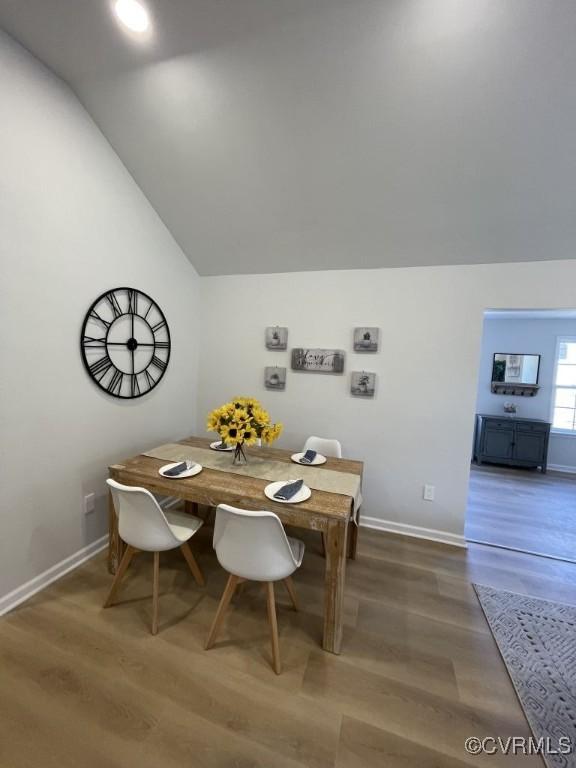 dining area with vaulted ceiling, wood finished floors, and baseboards