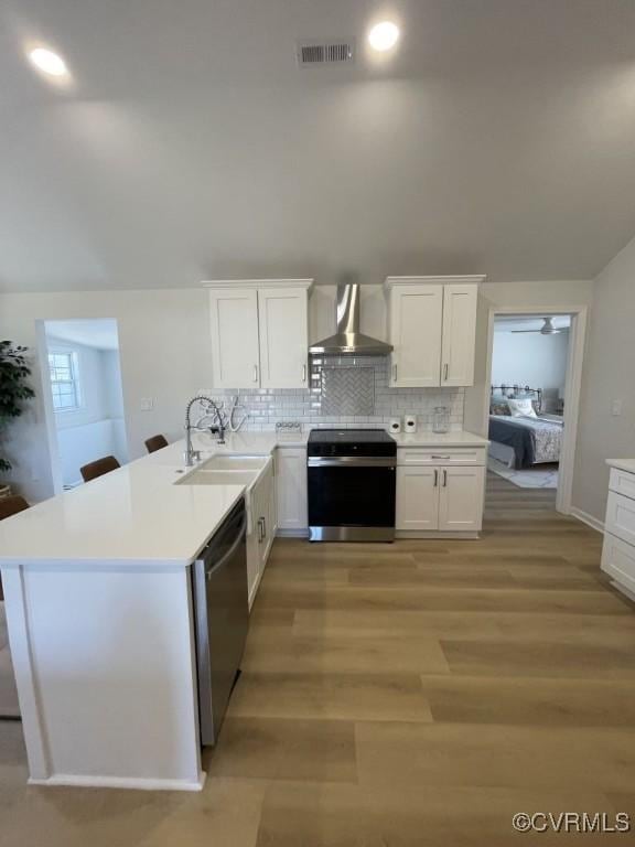 kitchen with stainless steel appliances, light countertops, visible vents, a sink, and wall chimney exhaust hood