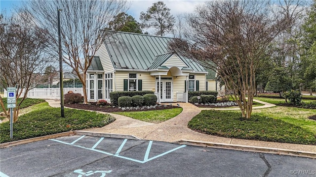 view of front of house with a standing seam roof, uncovered parking, a front lawn, french doors, and metal roof