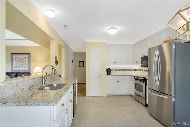 kitchen with ornamental molding, a sink, light stone counters, white cabinetry, and appliances with stainless steel finishes