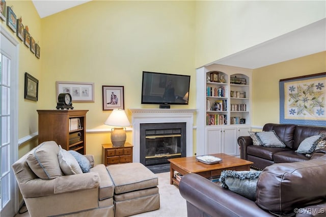 living area with built in features, baseboards, and a fireplace with flush hearth