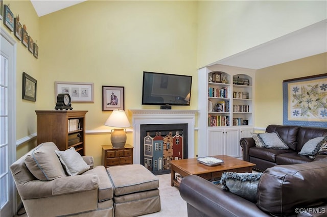 living room with built in features, baseboards, a towering ceiling, and a fireplace