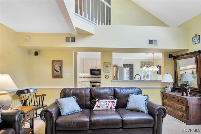 living room with a chandelier, visible vents, light colored carpet, and high vaulted ceiling