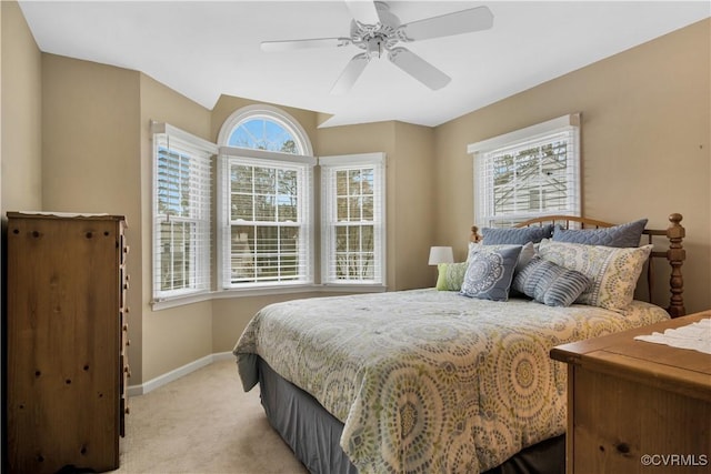 bedroom featuring light colored carpet, ceiling fan, baseboards, and multiple windows