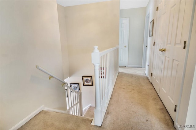 corridor featuring baseboards, an upstairs landing, and carpet flooring