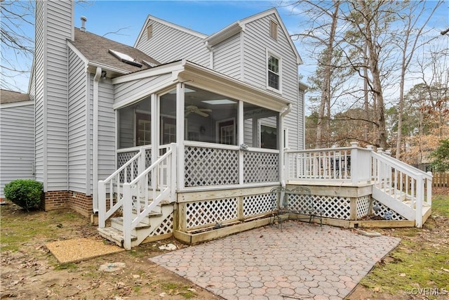 rear view of property with a wooden deck, stairway, a chimney, and a sunroom