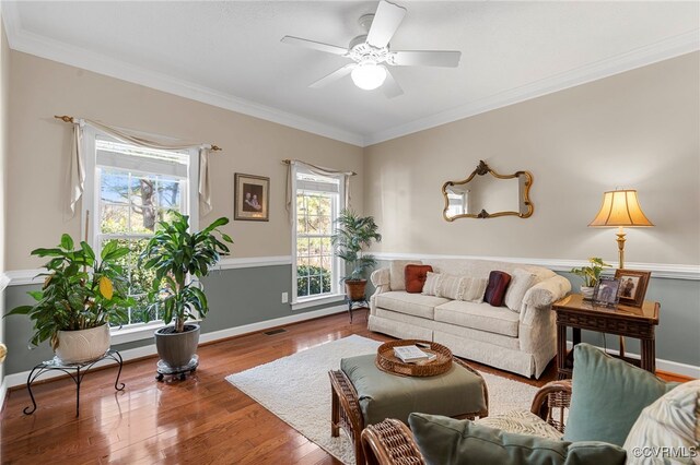 living room with crown molding, wood finished floors, baseboards, and a ceiling fan