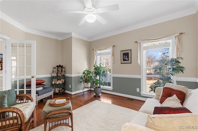 interior space with ceiling fan, ornamental molding, visible vents, wood finished floors, and baseboards