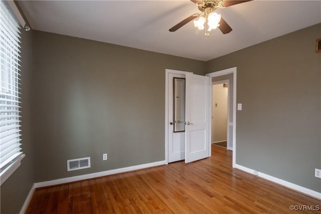 unfurnished room with a wealth of natural light, visible vents, light wood finished floors, and baseboards