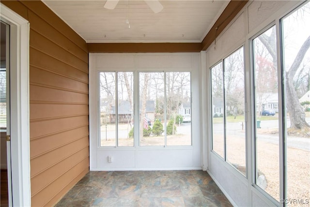 unfurnished sunroom featuring a healthy amount of sunlight, a residential view, and ceiling fan