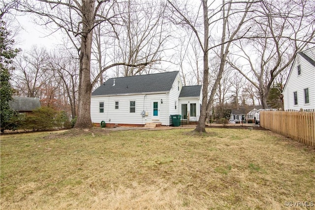 back of property featuring fence, a shingled roof, entry steps, french doors, and a lawn