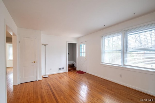 empty room featuring light wood-type flooring, baseboards, and visible vents