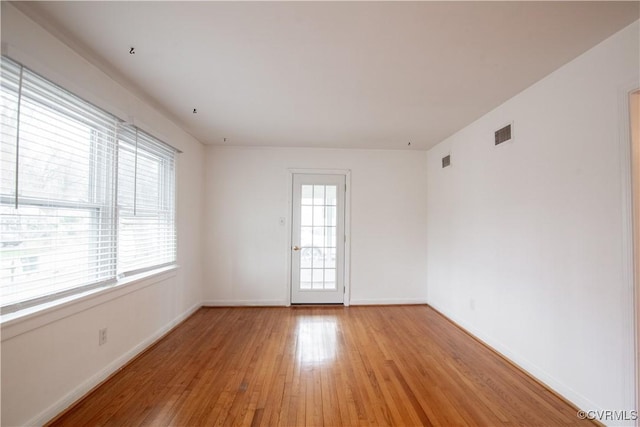 empty room with light wood-type flooring, baseboards, and visible vents