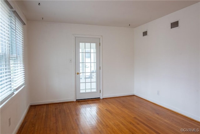 unfurnished room with baseboards, visible vents, and light wood finished floors