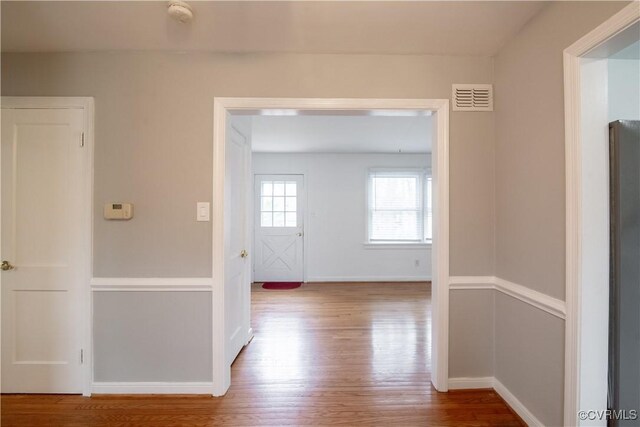 hallway with visible vents, baseboards, and wood finished floors