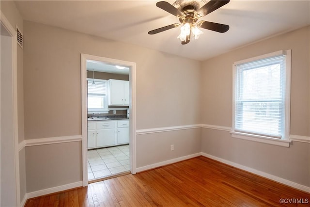 unfurnished room featuring a healthy amount of sunlight, baseboards, light wood-style floors, and a sink