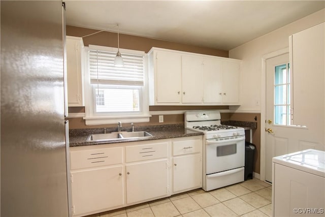 kitchen with white range with gas cooktop, washer / dryer, a sink, white cabinetry, and dark countertops