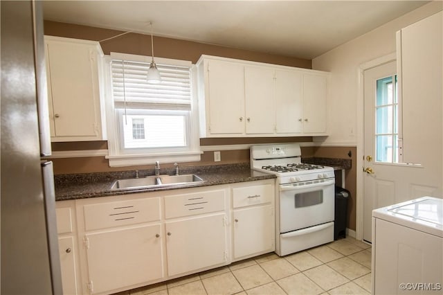 kitchen featuring a sink, plenty of natural light, dark countertops, and white gas stove