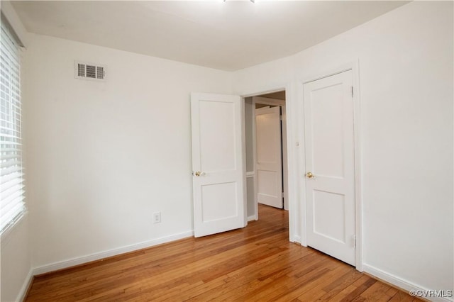 empty room with baseboards, visible vents, and light wood-type flooring