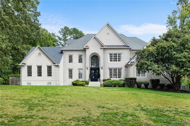 view of front of property with a front lawn, cooling unit, and brick siding