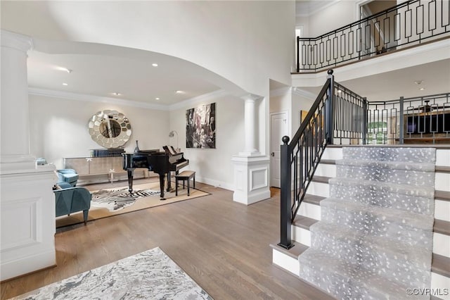 foyer entrance with arched walkways, ornamental molding, wood finished floors, and decorative columns