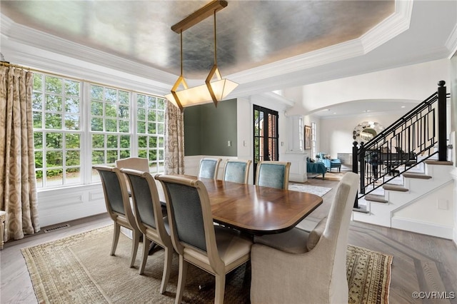 dining area featuring arched walkways, crown molding, visible vents, stairway, and wood finished floors