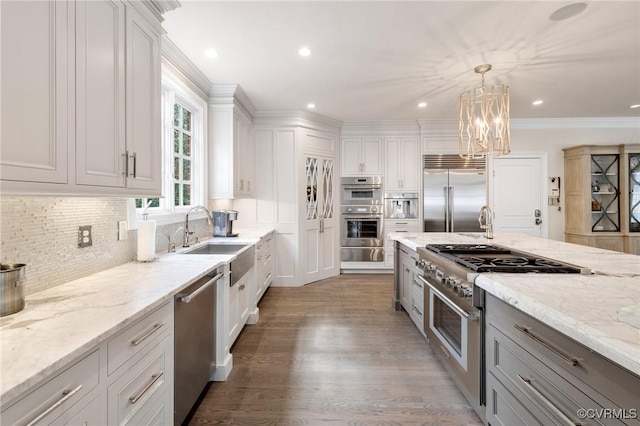 kitchen with premium appliances, a sink, backsplash, and light stone countertops