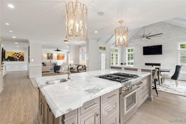 kitchen featuring high end stove, open floor plan, a sink, and ceiling fan with notable chandelier