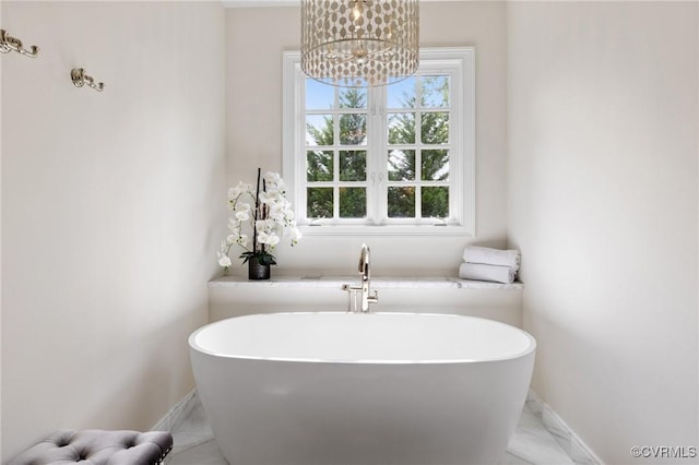 full bathroom with marble finish floor, a soaking tub, and baseboards