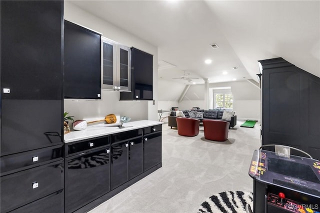 kitchen featuring visible vents, a ceiling fan, light colored carpet, lofted ceiling, and dark cabinetry