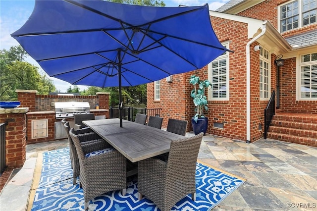 view of patio with exterior kitchen, outdoor dining space, fence, and grilling area