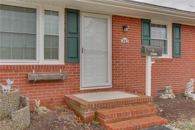 property entrance featuring crawl space and brick siding